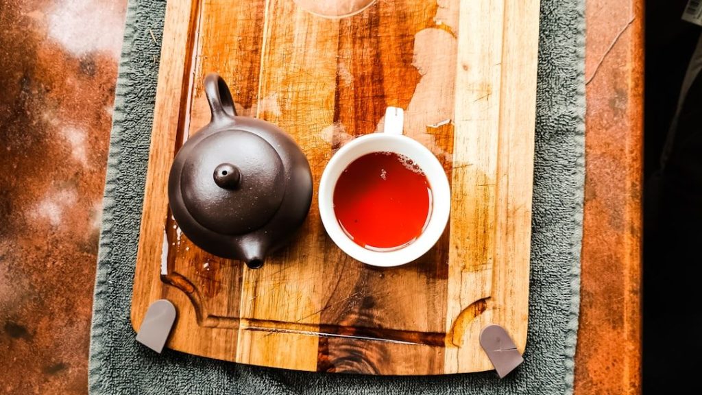 Théière et tasse de thé fumante sur un plateau en bois, symbole d'une pause apaisante pour calmer le stress et la digestion