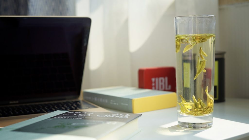 Verre de thé fumant posé sur un bureau à côté d un ordinateur portable, pause pour apaiser le stress au travail