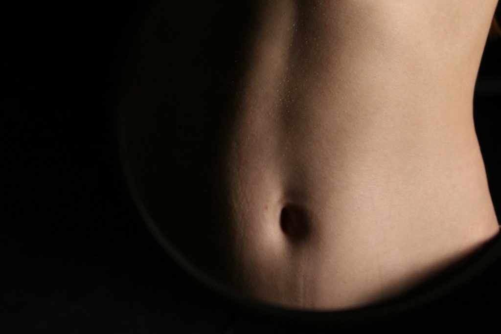 Femme tenant son ventre gonflé et dur des deux mains